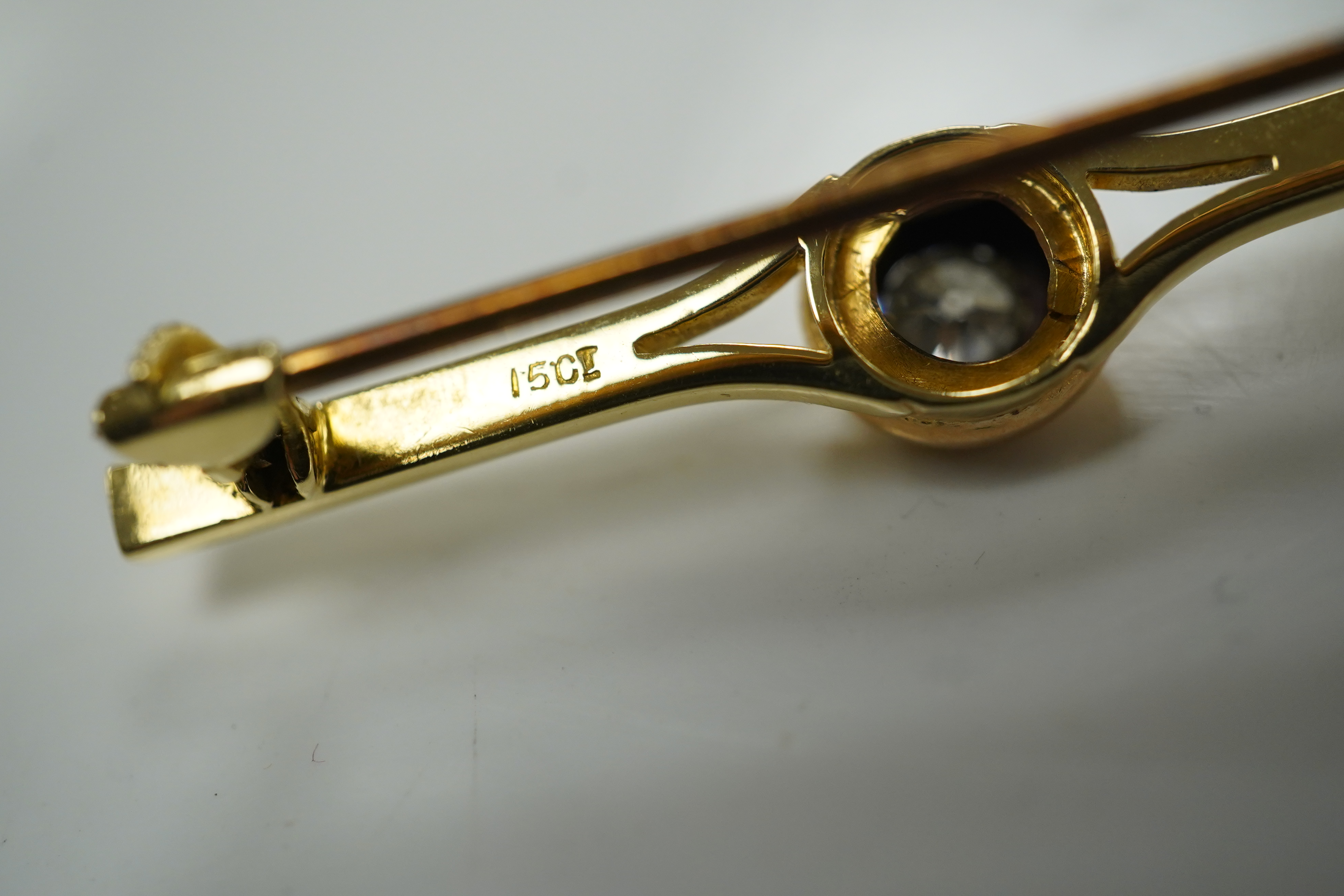 An early 20th century 15ct and solitaire diamond set bar brooch, 44mm, gross 3.5 grams and a similar 15ct, ruby and seed pearl set ribbon bow bar brooch, 2.4 grams. Condition - fair to good